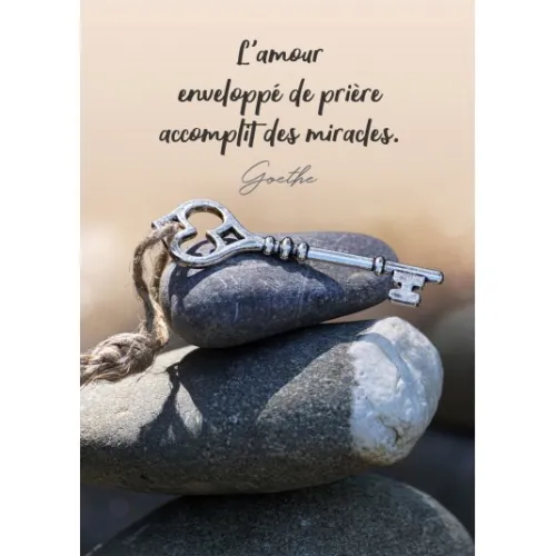 Carte postale clé posée sur une pile de galets